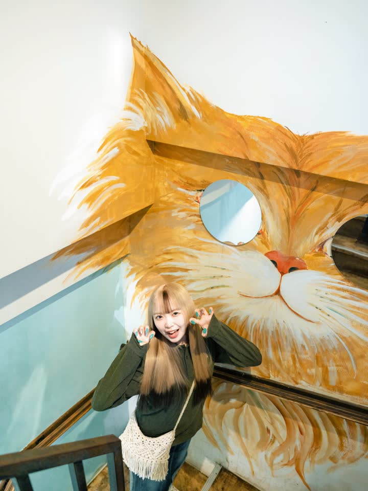 階段の踊り場。大きな猫の壁画と、スタッフのひなこちゃん